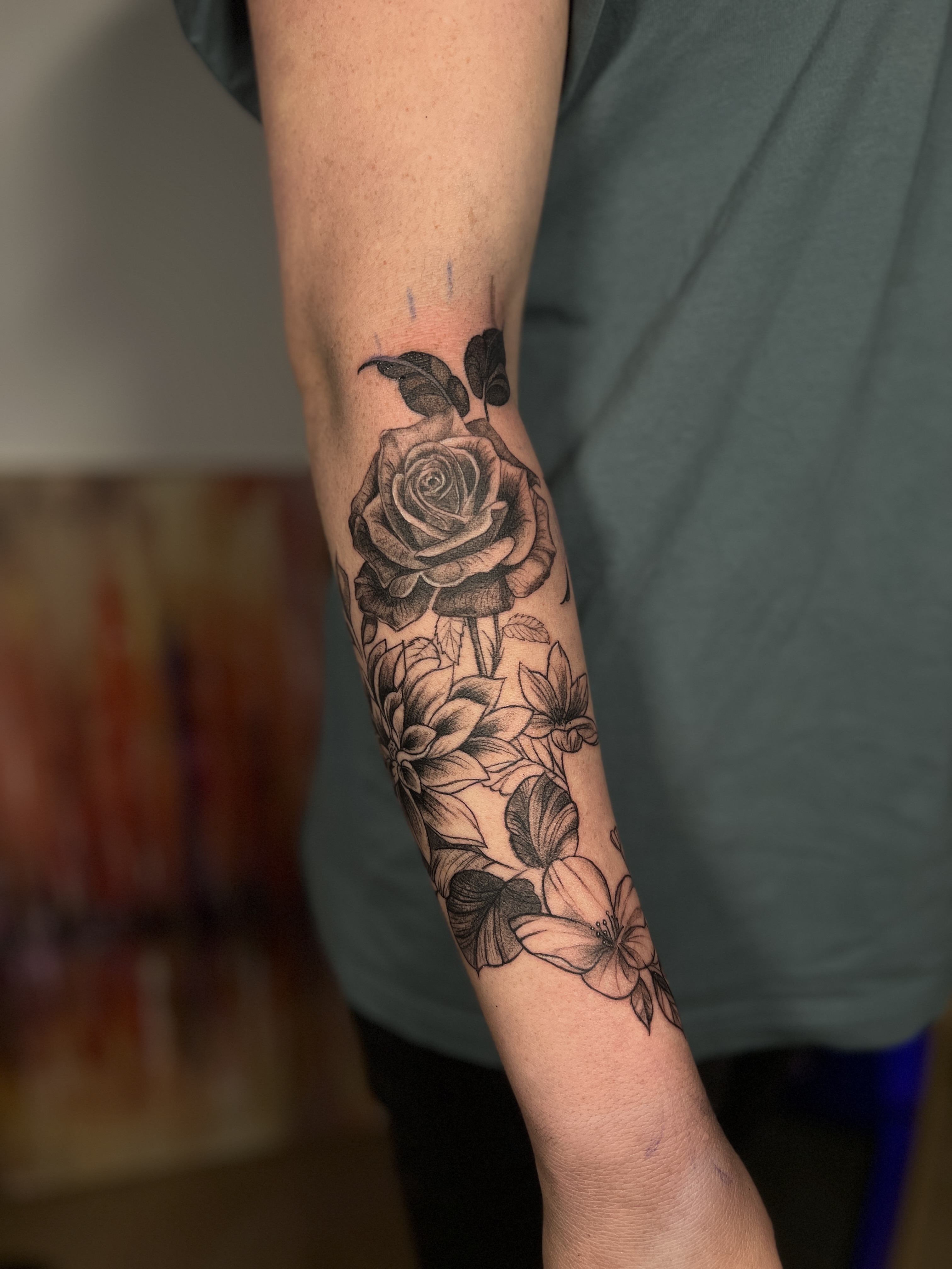 Blackwork bloemen tattoo met roos op onderarm.