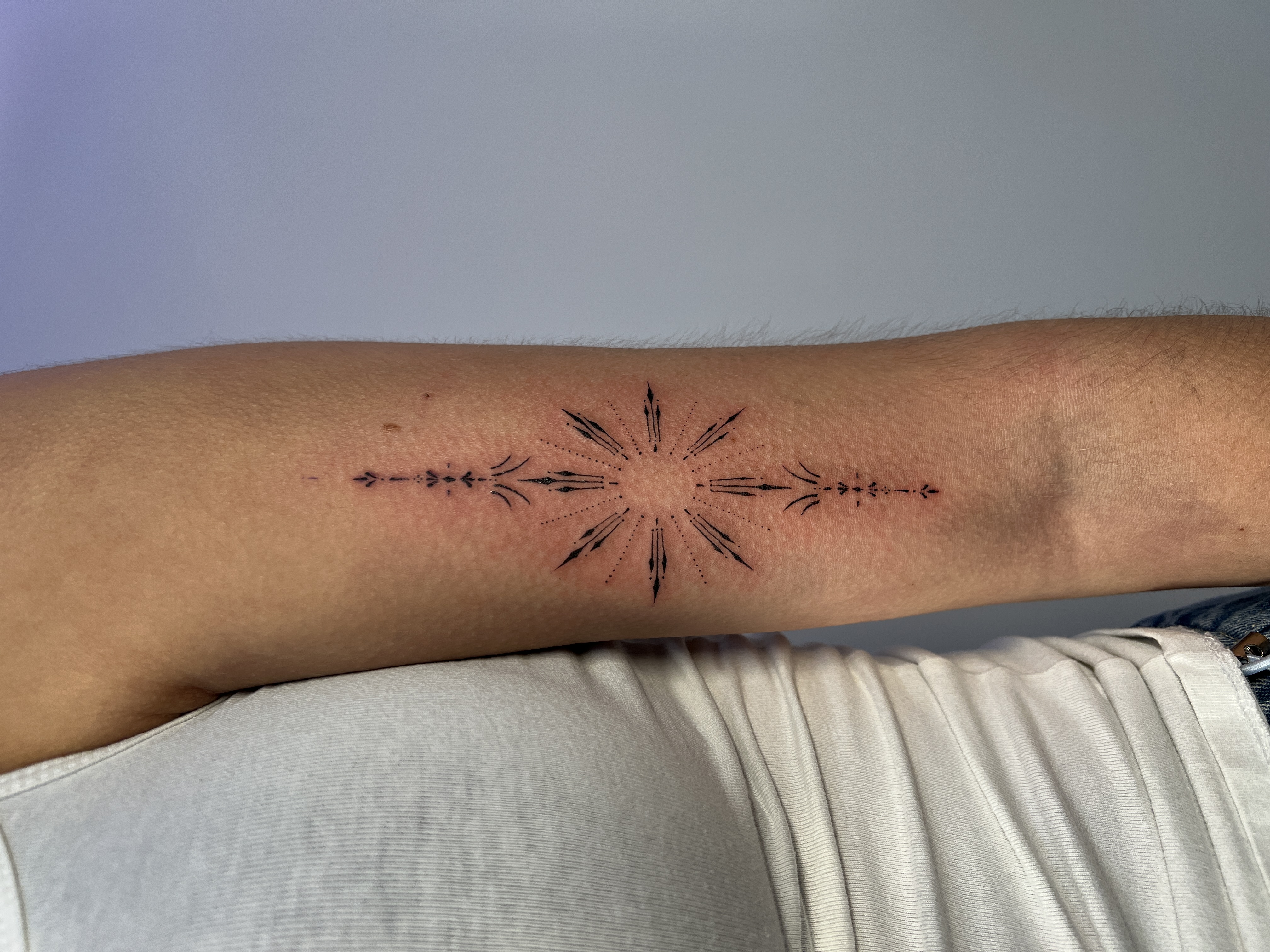 Fineline ornamentale ster tattoo op bovenarm met dotwork details.