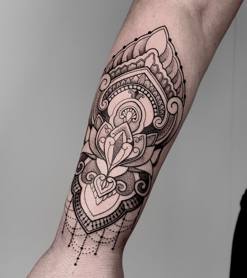 Gedetailleerde ornamental mandala tattoo op de onderarm.