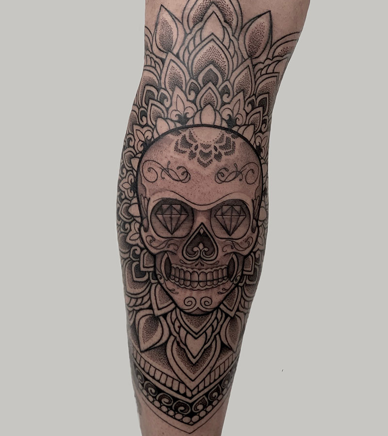 Grote dotwork suikerschedel met diamanten ogen en mandala op onderbeen.