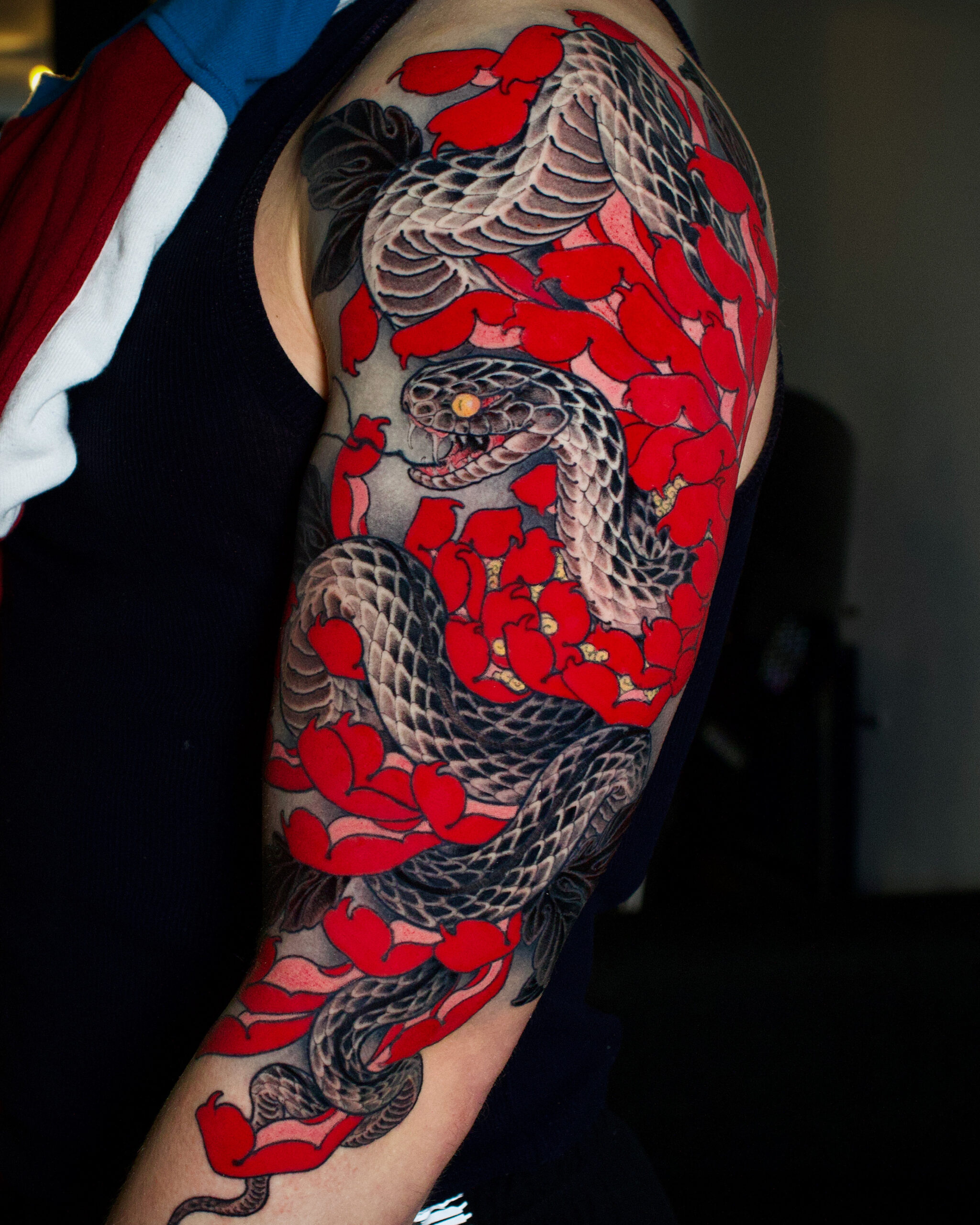 Japanse slang en rode bloemen op bovenarm.