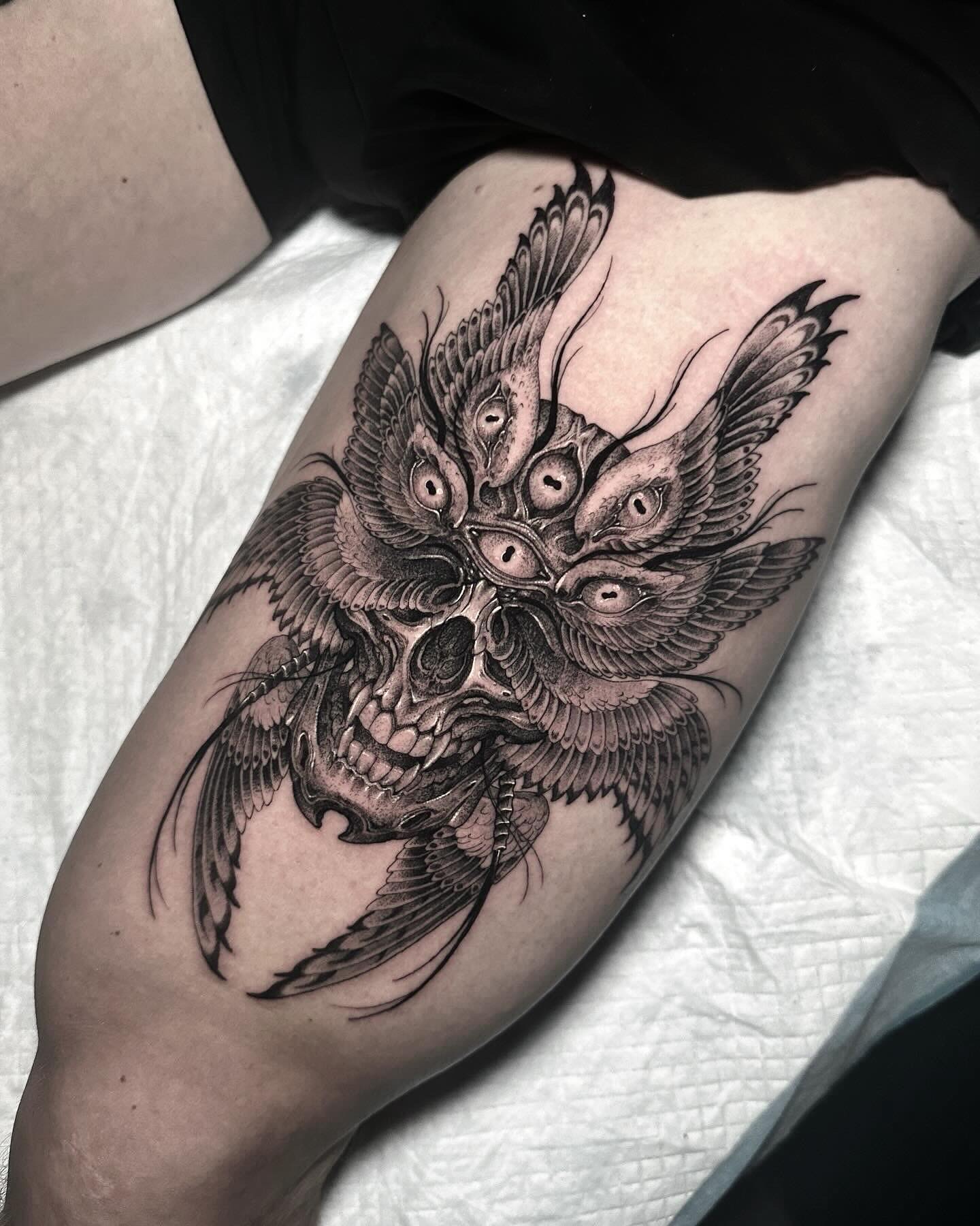 Gedetailleerde schedel met meerdere ogen en vleugels op bovenbeen.