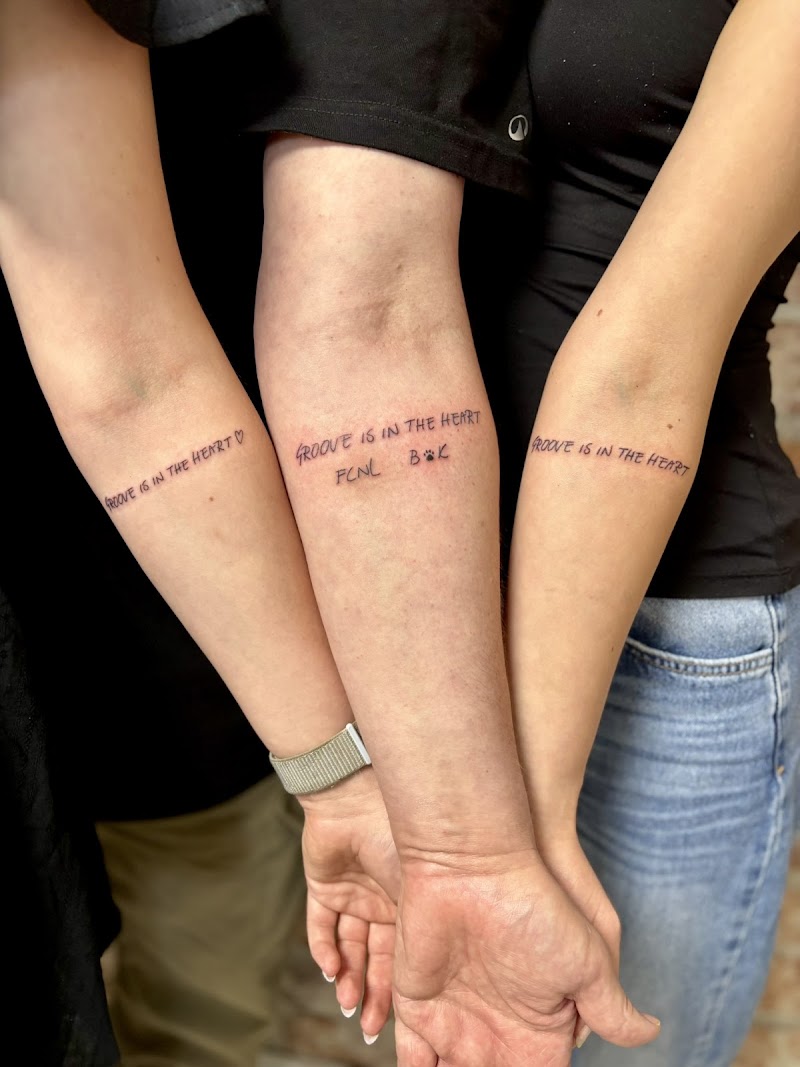 Drie bijpassende teksttattoos 'GROOVE IS IN THE HEART' op onderarmen.