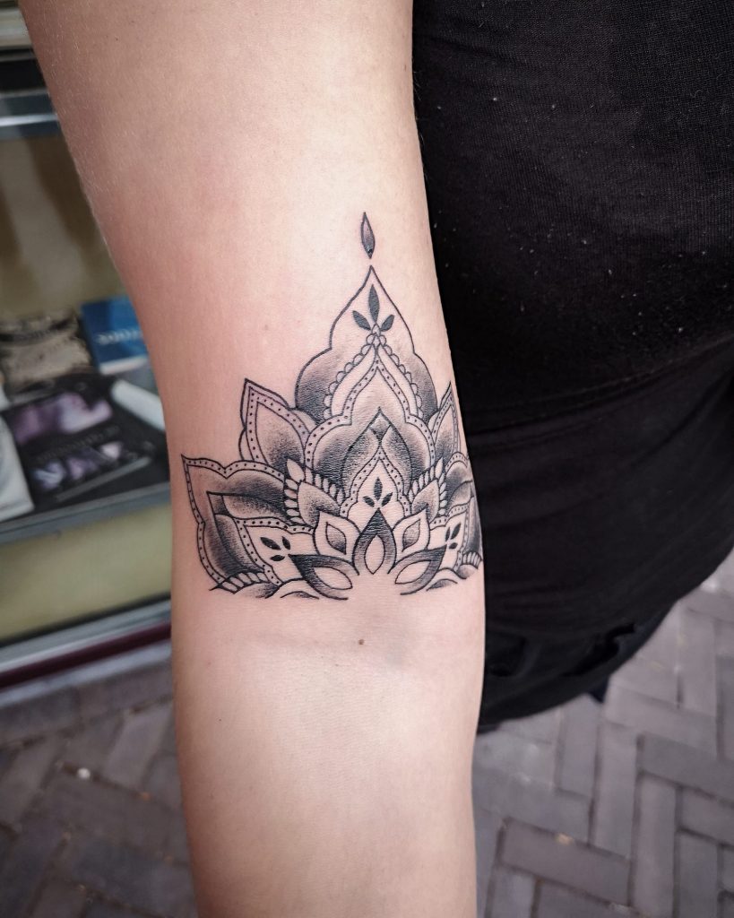 Zwart-wit mandala lotus tattoo op de bovenarm met dotwork details.