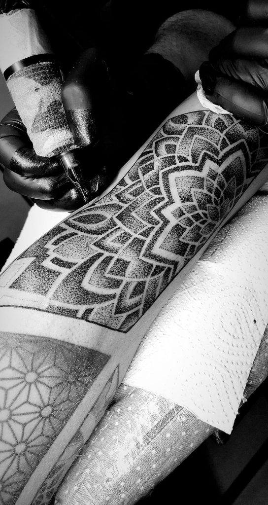 Grote dotwork mandala tattoo op onderarm tijdens het zetten.
