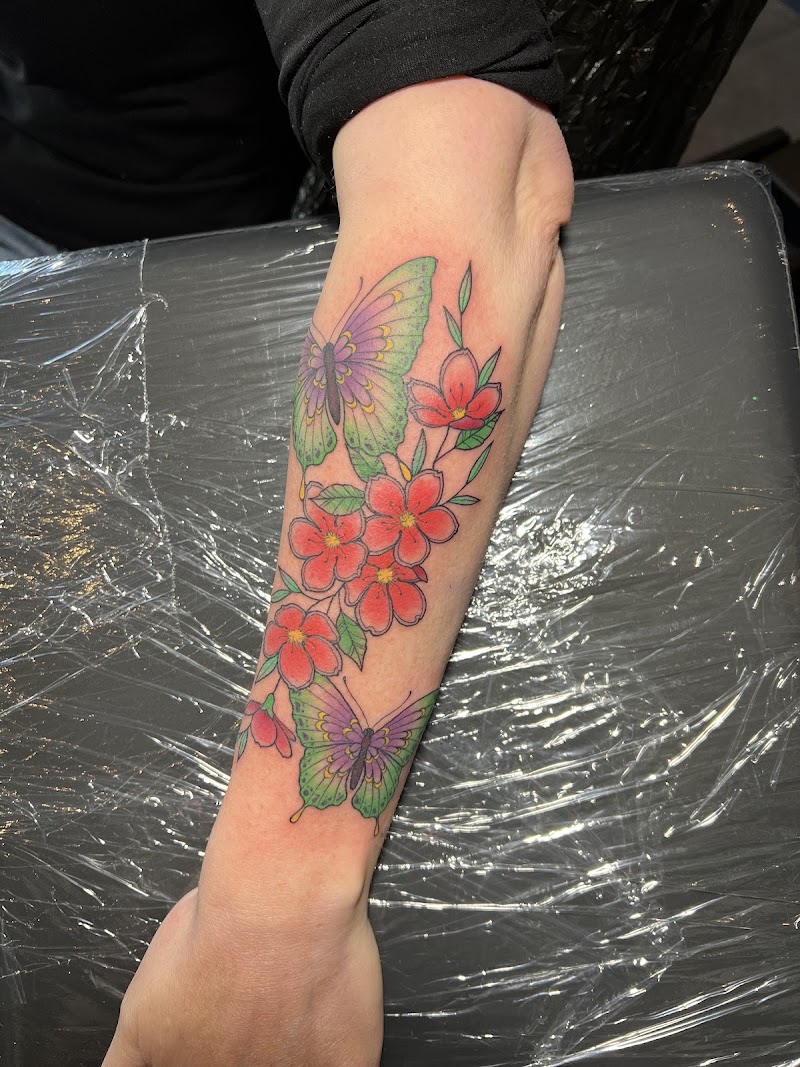 Kleurrijke vlinders en bloemen op onderarm.