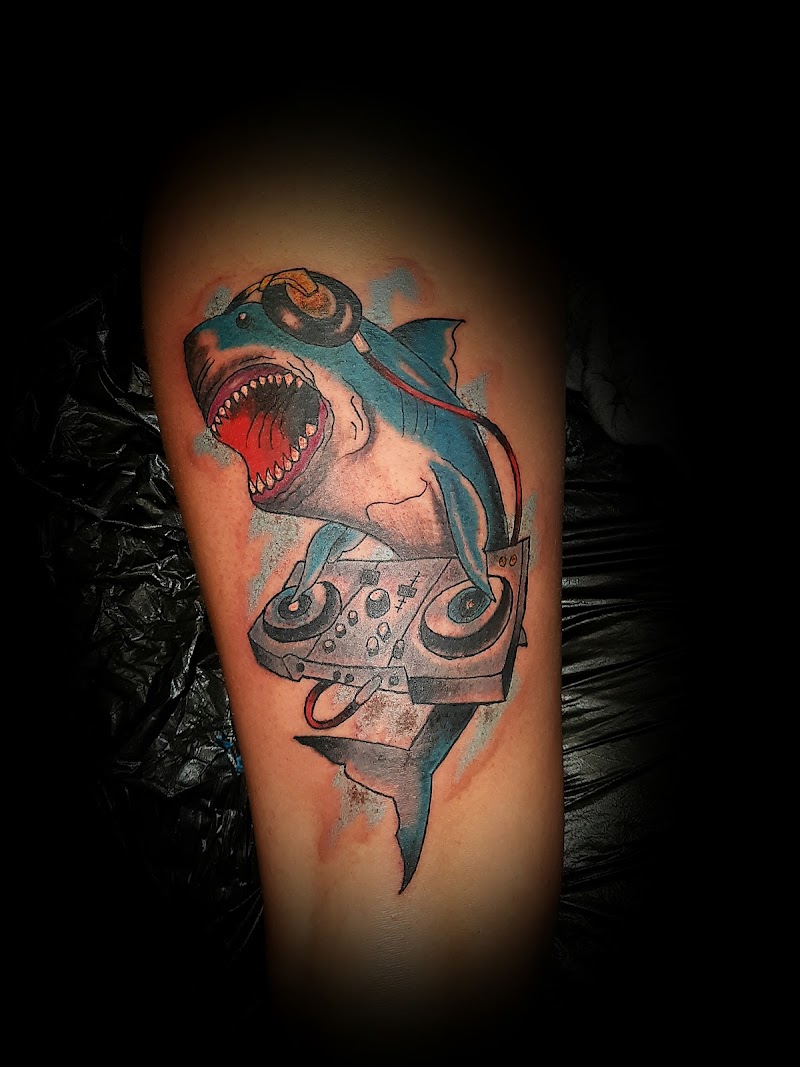 Kleurrijke tattoo van een DJ haai met koptelefoon en mengpaneel.