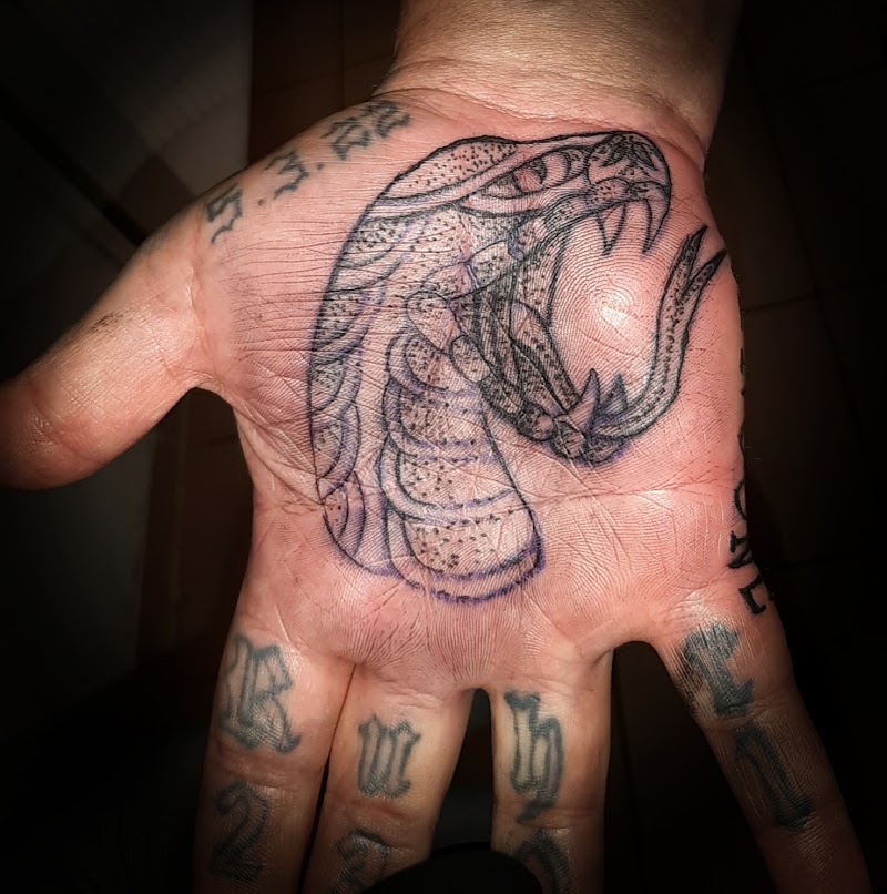 Slangenkop tattoo in handpalm, met stencil lijnen nog zichtbaar.