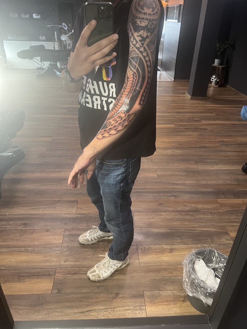 Polynesische tribal sleeve tattoo met masker op bovenarm.