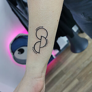 Minimalistische geometrische tattoo met cirkels en stippen op onderarm