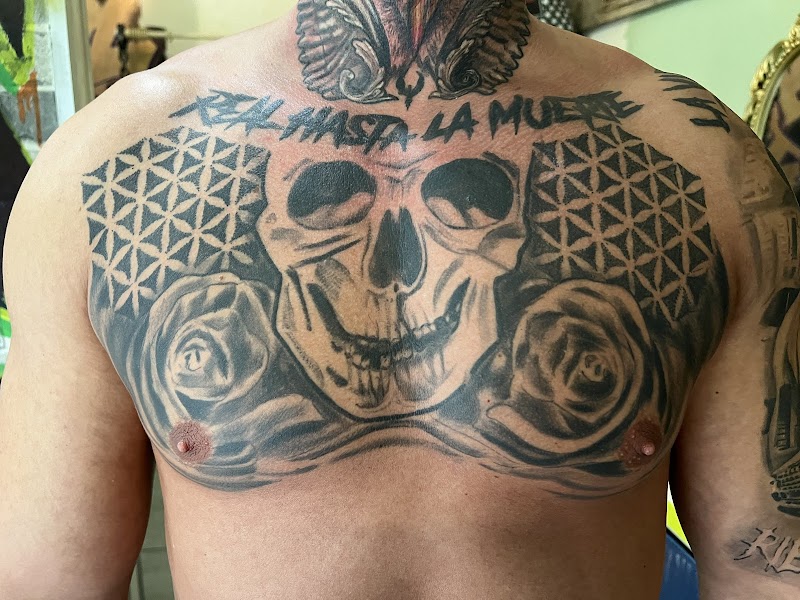 Grote borsttattoo met schedel, rozen en tekst "REAL HASTA LA MUERTE".
