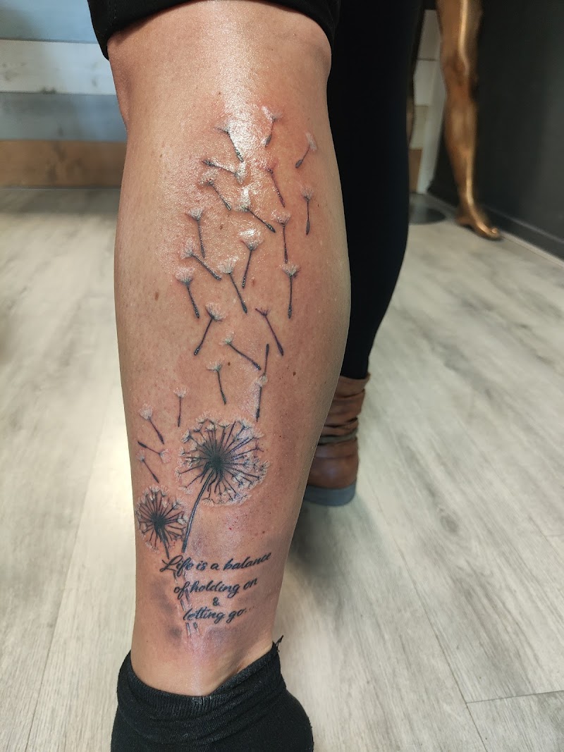 Paardenbloemen met wegvliegende pluisjes en tekst op onderbeen.