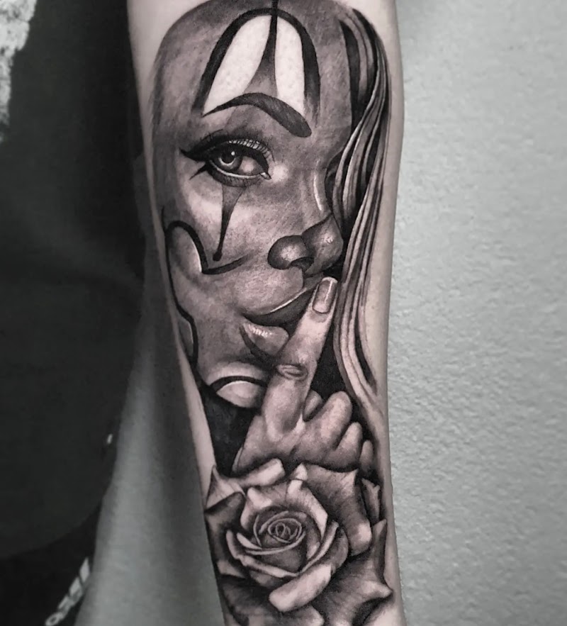 Zwart-wit tattoo van een clownvrouw die 'ssst' gebaart, met een roos eronder.