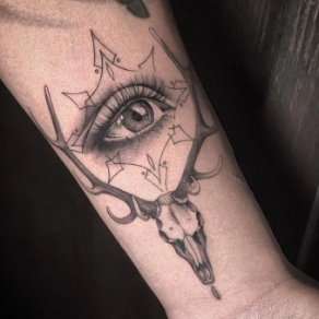 Blackwork tattoo van een herten schedel met een realistisch oog in een geometrisch frame.