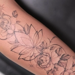 Fineline bloemen tattoo met lotus en pioenen op onderarm.