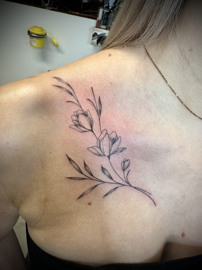 Fineline bloementak op sleutelbeen en schouder.