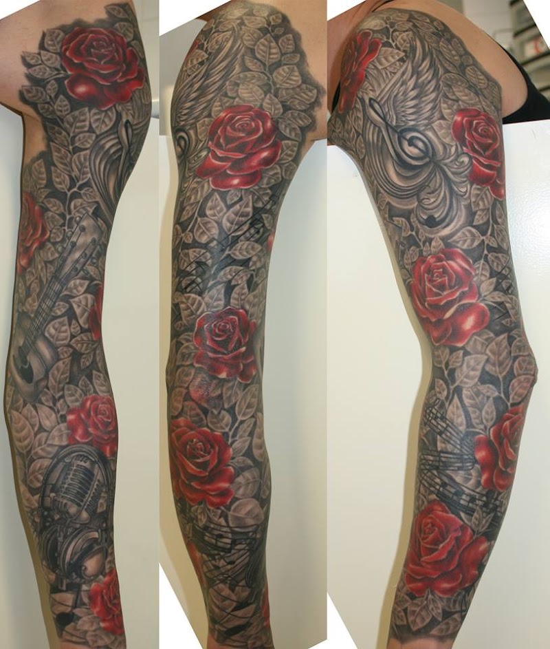 Sleeve tattoo met rode rozen, gitaar, microfoon en muzieknoten in zwart-wit.