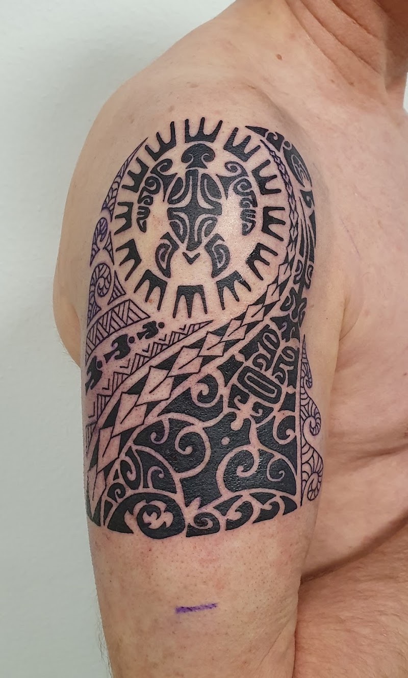 Grote Polynesische tribal tattoo op de bovenarm met een schildpad en zon.