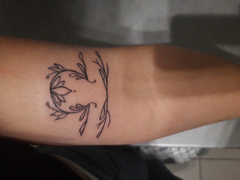 Fineline tattoo van het sterrenbeeld Weegschaal met bloemen en takken.