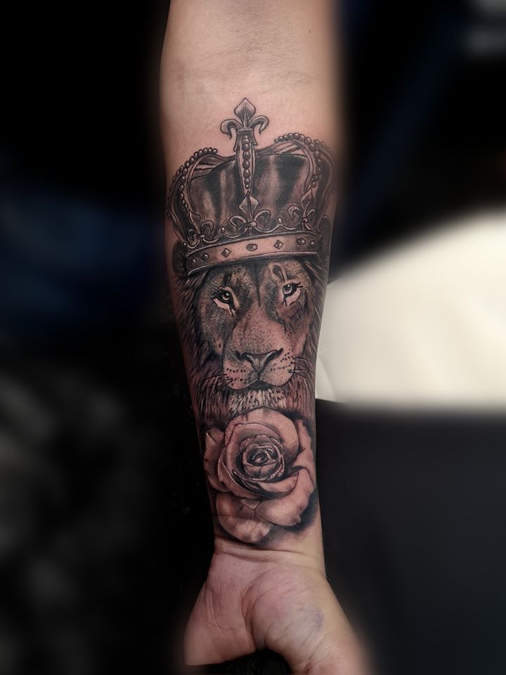 Realistische leeuw met kroon en roos op onderarm.