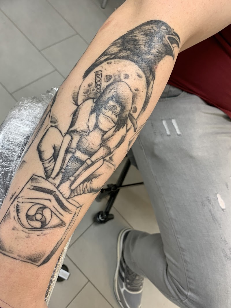 Zwart-wit tattoo van Itachi Uchiha met kraai en Sharingan oog op onderarm.