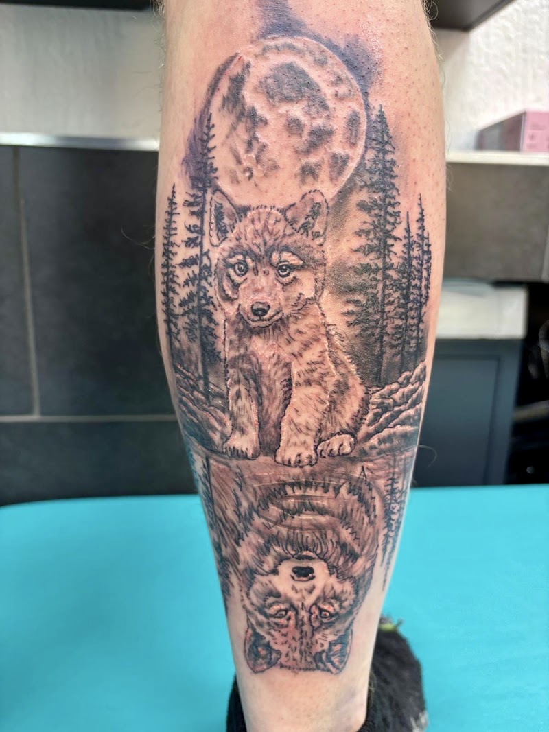 Realistische tattoo van wolf welp met reflectie van volwassen wolf, maan en bos.
