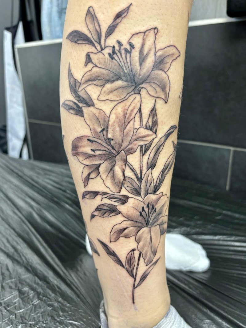 Zwart-wit lelie bloemen tattoo op onderbeen.