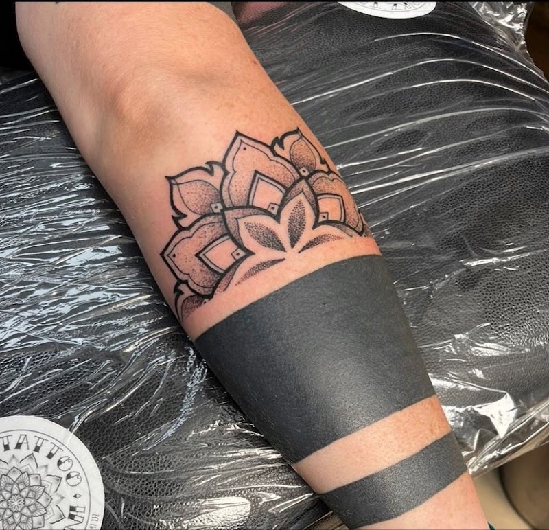 Mandala met dotwork en brede blackwork banden op onderarm.