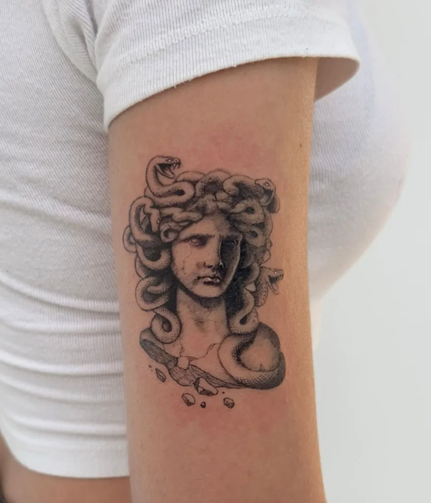 Realistische Medusa buste tattoo op bovenarm.