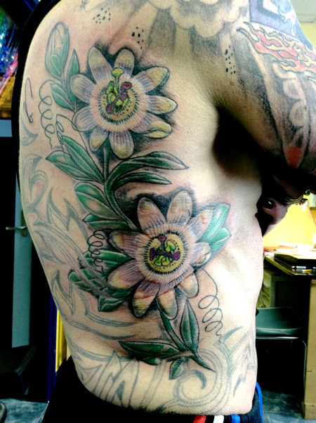 Gekleurde passiebloemen met bladeren en ranken op de ribben.