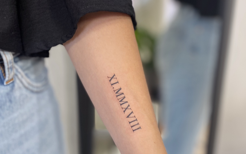 Romeinse cijfers XI.MMXVIII op onderarm