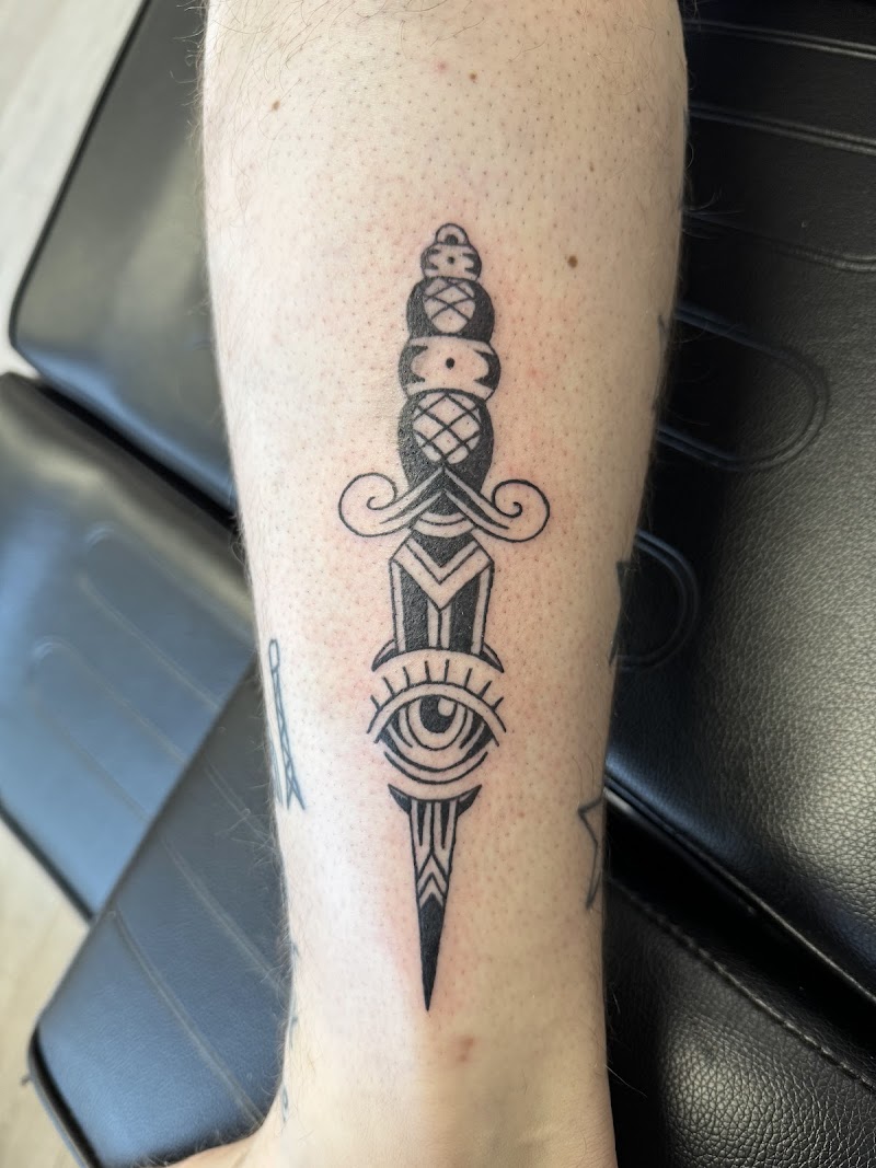 Zwart-wit traditionele dolk met een alziend oog op het onderbeen.