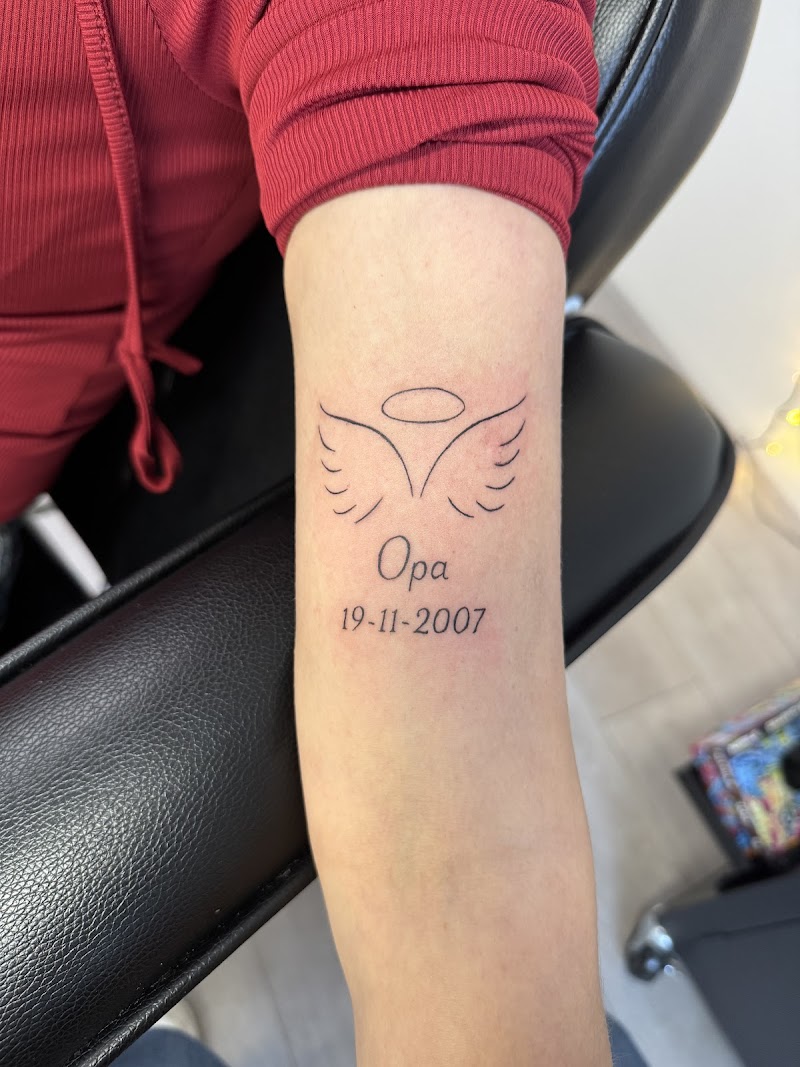 Fineline herdenkingstattoo met vleugels, halo, 'Opa' en datum.