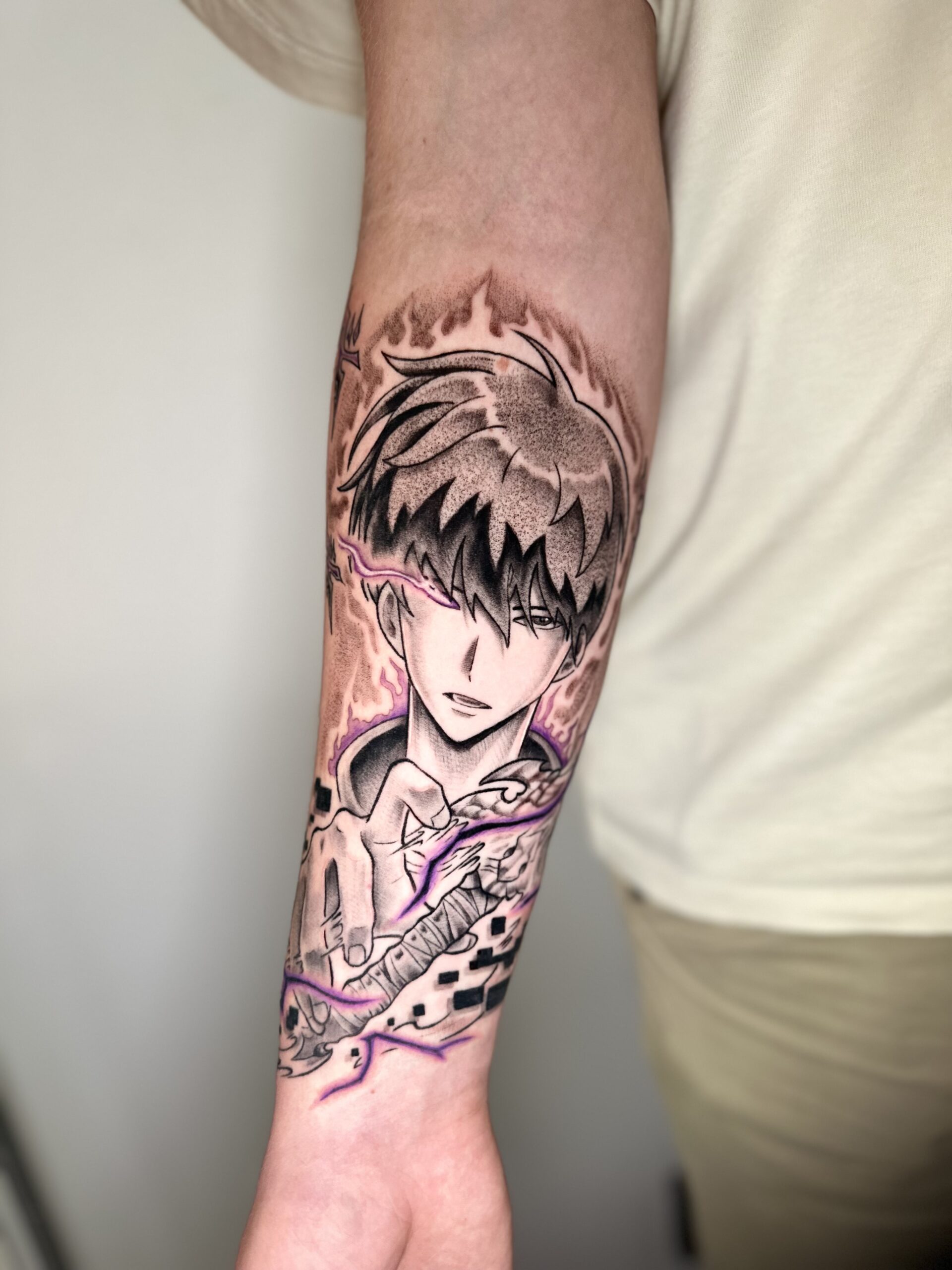 Anime karakter tattoo met paarse energie op onderarm.
