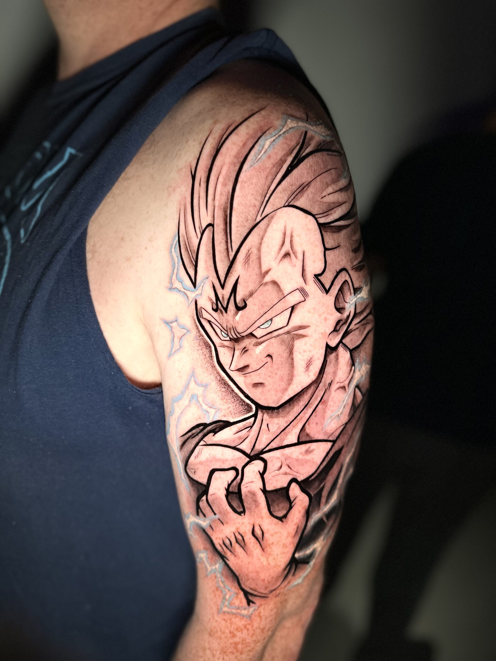 Illustratieve Majin Vegeta tattoo met blauwe bliksem op bovenarm.