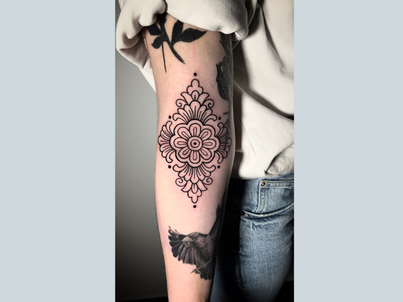 Ornamentale mandala tattoo met bloemmotief op de achterkant van de bovenarm.