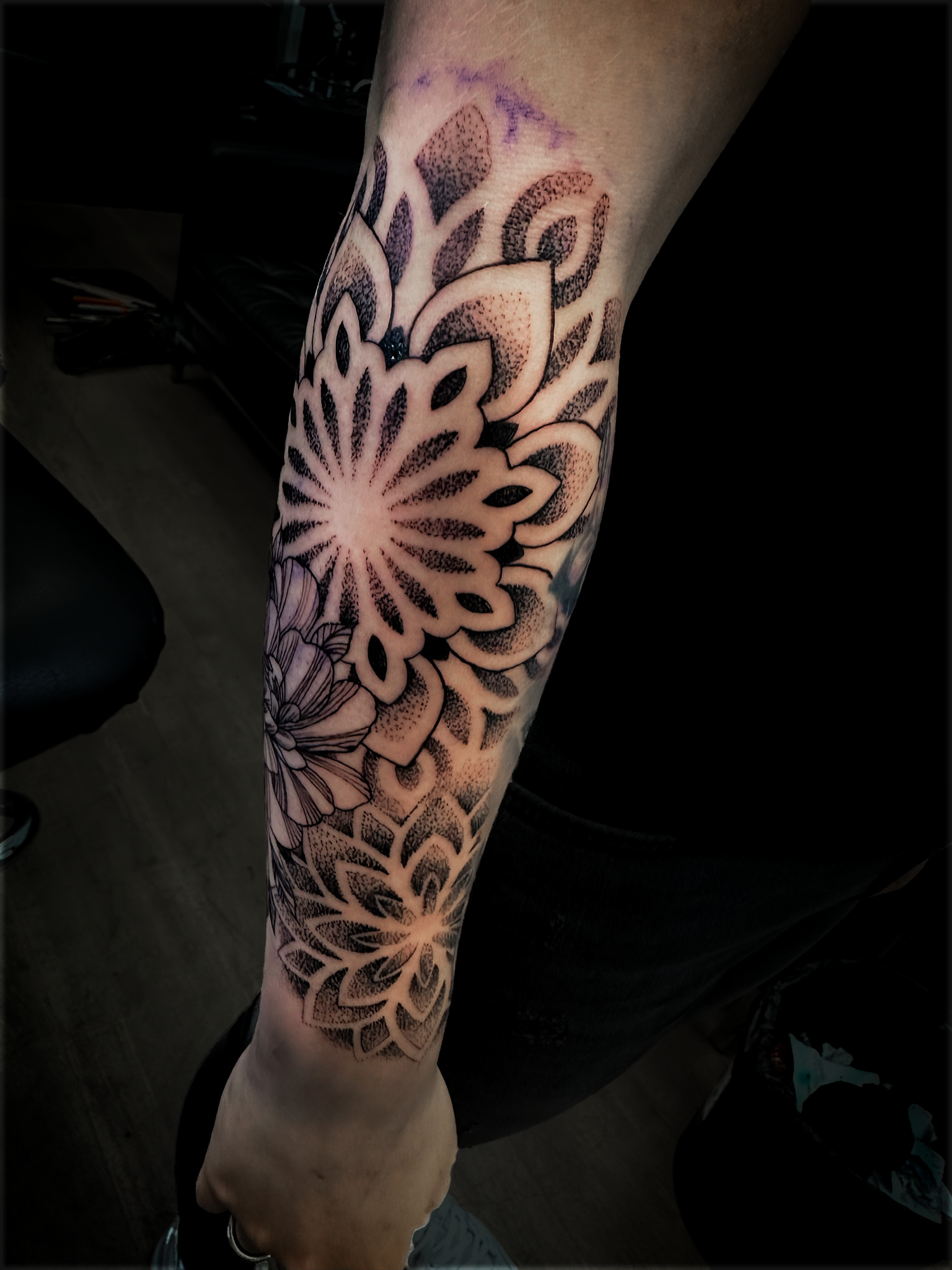 Grote dotwork mandala en bloem tattoo op de onderarm.