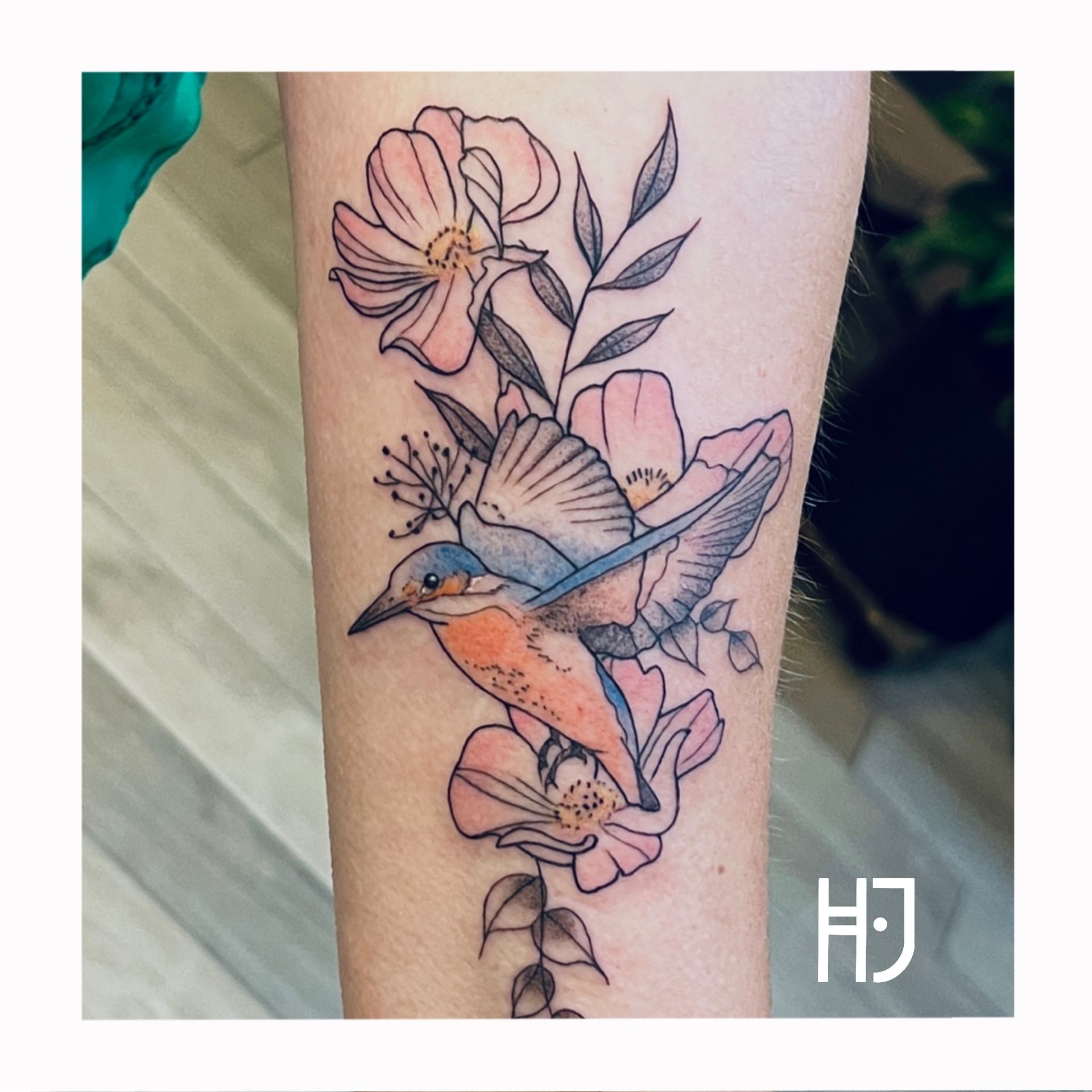 Kleurrijke ijsvogel met bloemen op onderarm.