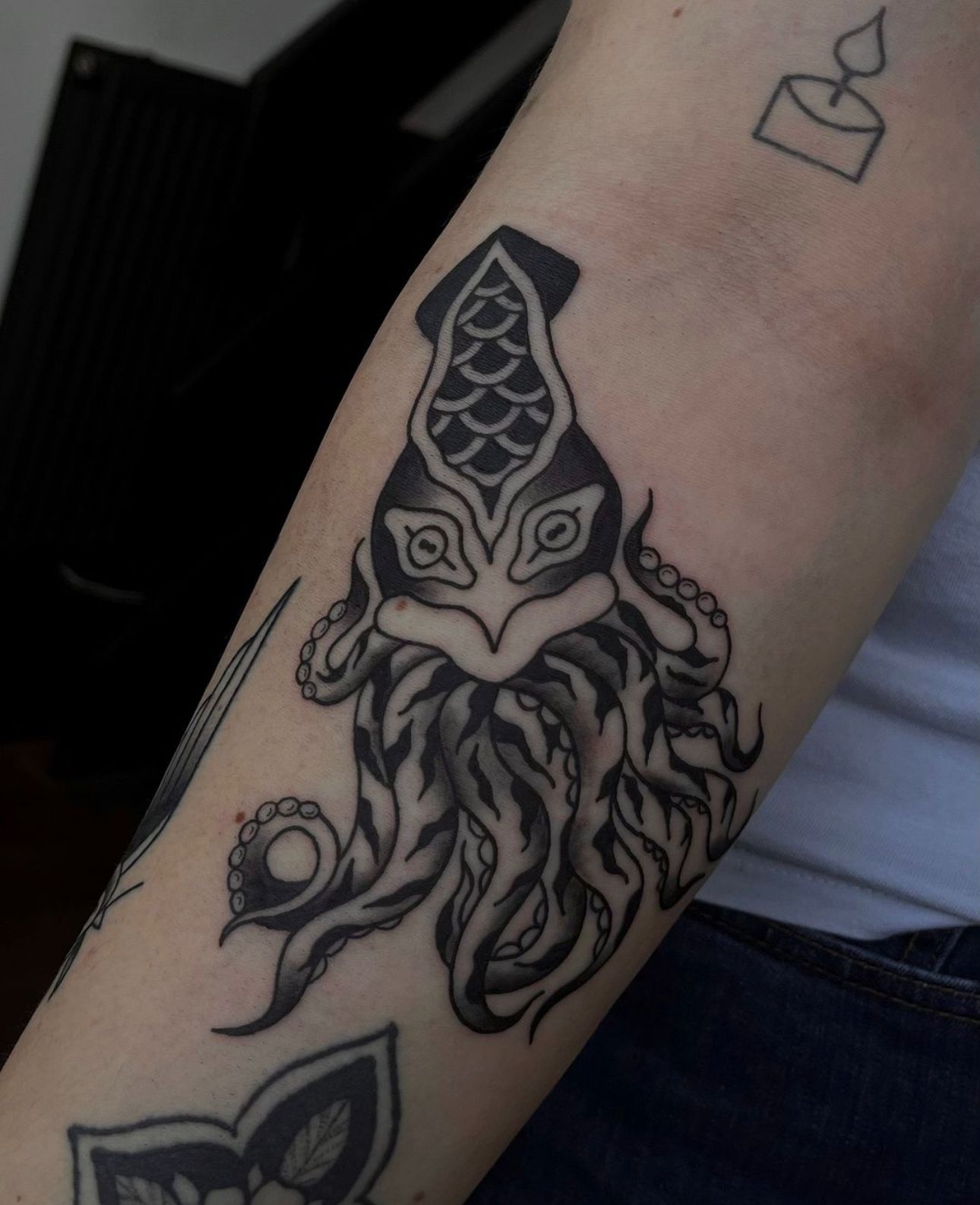 Zwart-wit inktvis tattoo in traditionele stijl op de bovenarm.