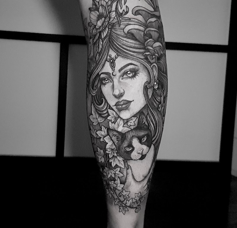 Zwart-wit portret van een vrouw met een kat en bladeren op het onderbeen.