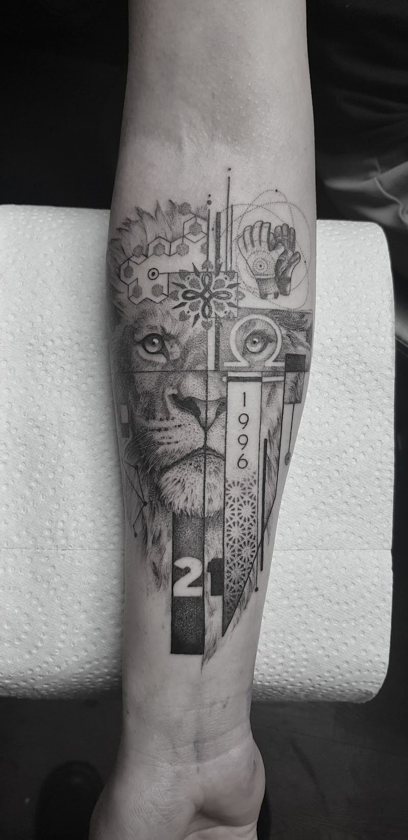 Geometrische leeuw met jaartal 1996 en nummer 21 op onderarm.