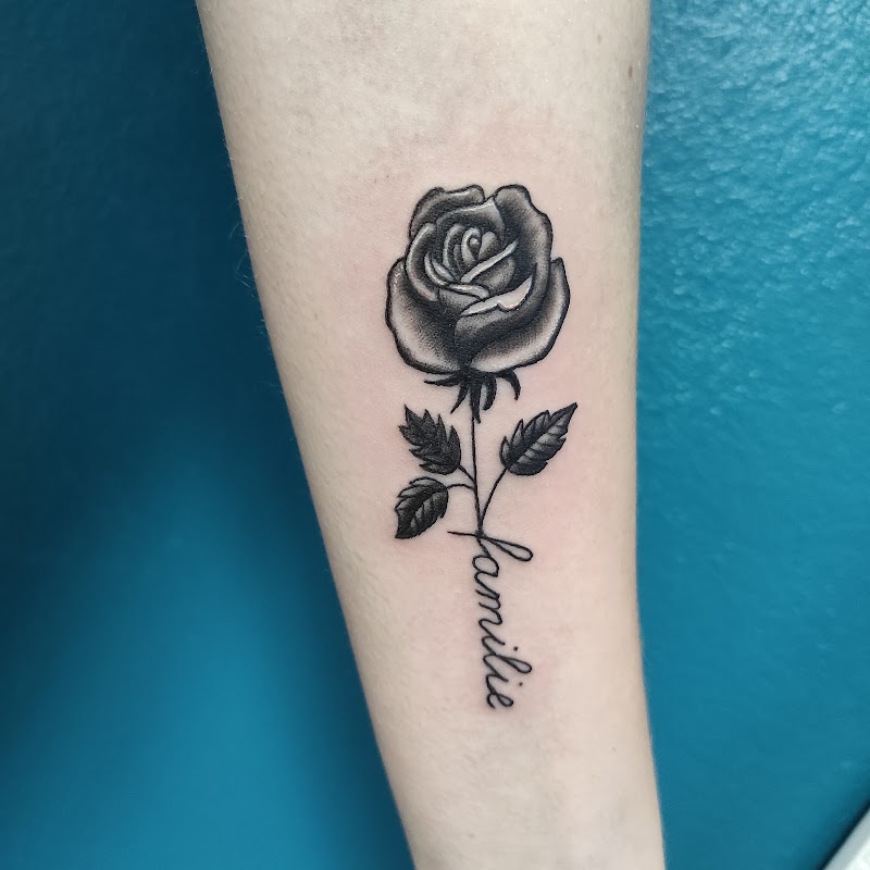 Zwart-grijze roos met 'familie' tekst op onderarm.