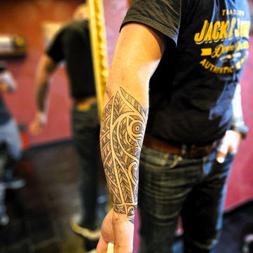 Polynesische tribal tattoo met geometrische patronen op onderarm.