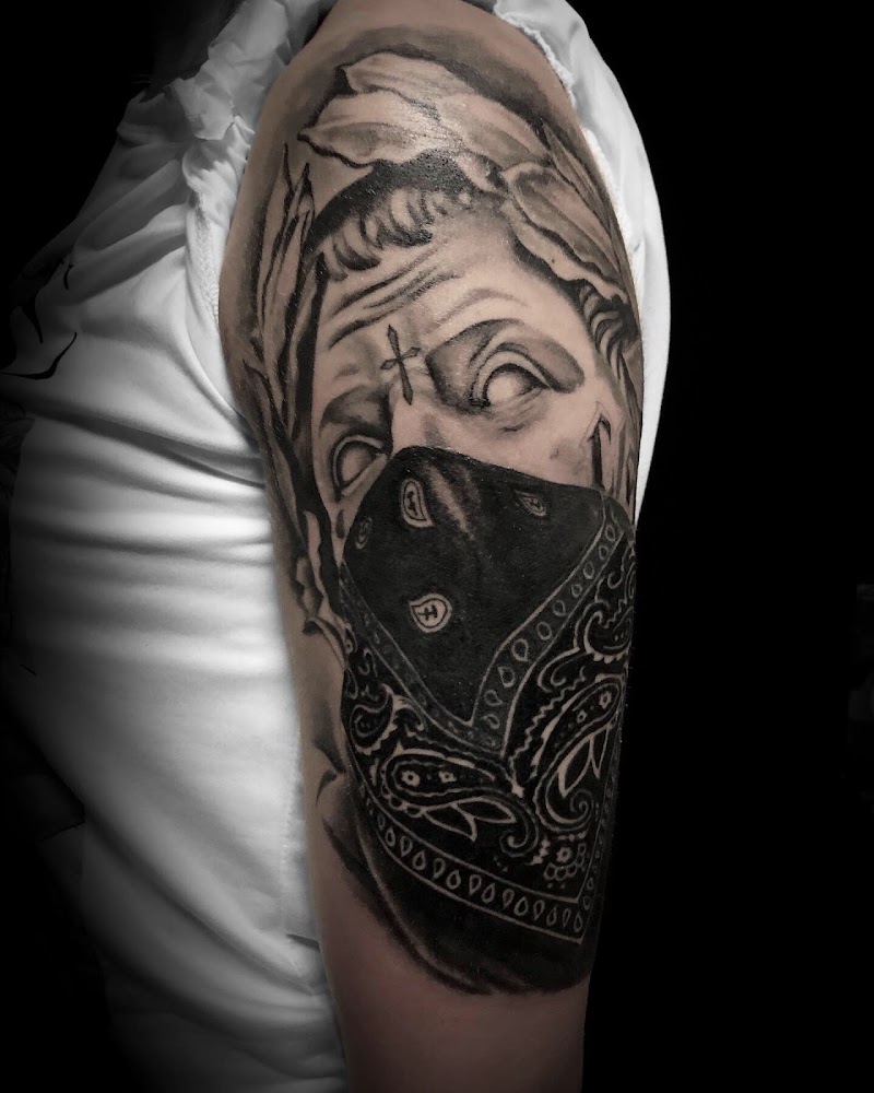Blackwork tattoo van een klassiek standbeeld met een bandana en kruisje.