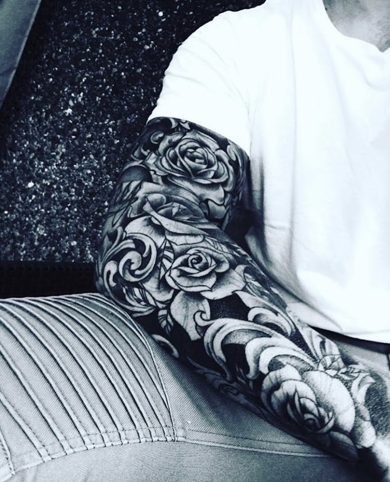 Zwart-wit sleeve tattoo met realistische rozen en filigraan.