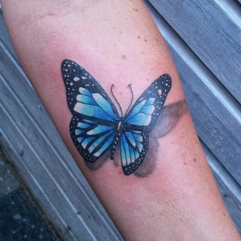 Realistische blauwe vlinder met 3D schaduw op onderarm.