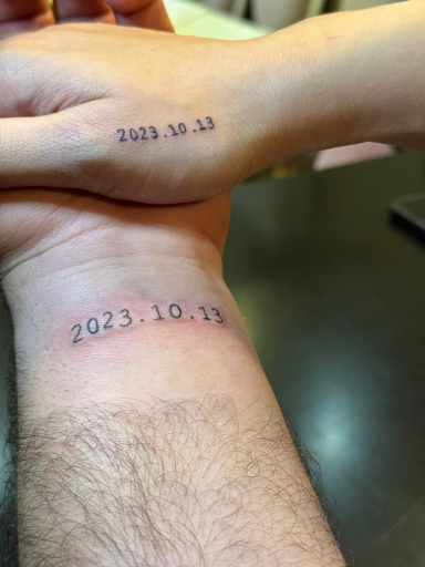 Twee minimalistische datum tattoos '2023.10.13' op polsen.