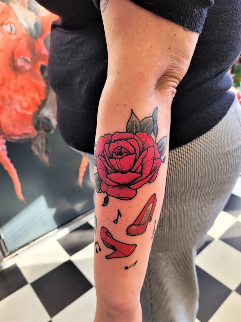 Rode roos en rode hakken met muzieknoten op onderarm.