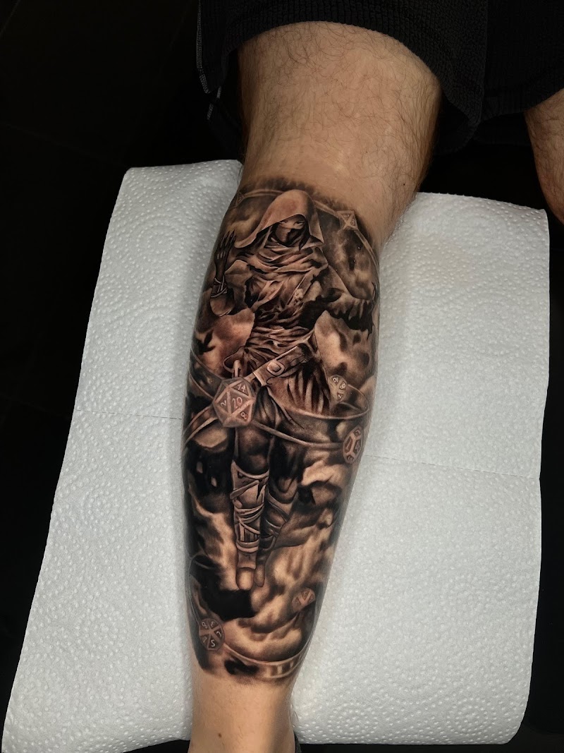 Realistische tattoo van een figuur met kap en dobbelstenen op het onderbeen.