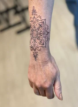 Gedetailleerde mandala tattoo op de pols en onderarm.